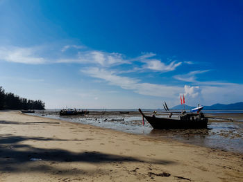 Fishing boat on beach against sky