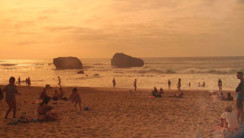 People on beach against sky during sunset