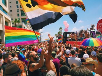 People with multi colored flags against sky