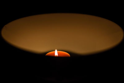 Close-up of lit candle in dark room