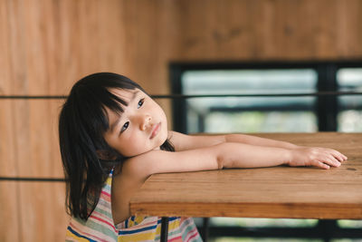 Thoughtful girl leaning on wooden table