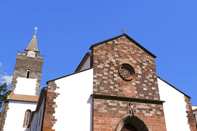 Low angle view of clock tower amidst buildings against clear sky