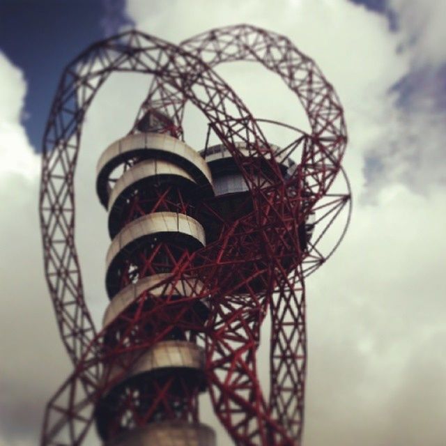 low angle view, sky, built structure, ferris wheel, architecture, cloud - sky, amusement park, arts culture and entertainment, amusement park ride, building exterior, metal, cloudy, cloud, day, tower, outdoors, no people, tall - high, metallic, focus on foreground