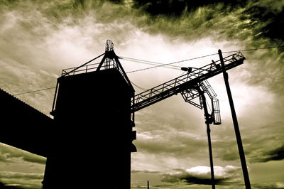 Low angle view of silhouette crane against sky