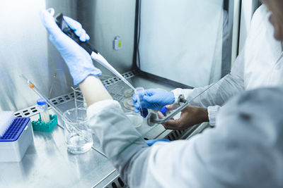 Scientist with colleague taking liquid solution with pipette