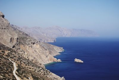 Scenic view of sea and mountains against clear blue sky