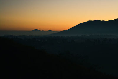 Scenic view of silhouette mountains against orange sky