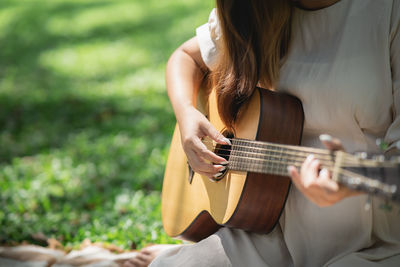 Midsection of woman playing guitar