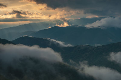 Scenic view of mountains against dramatic sky during sunset