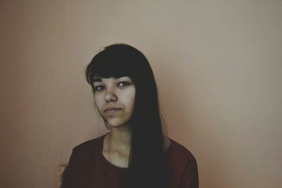 Portrait of young woman against wall