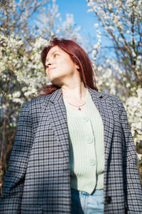 Young woman standing against trees