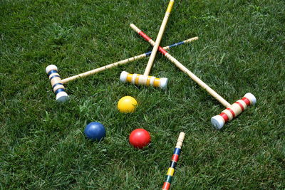 High angle view of multi colored croquet balls and mallets on grass lawn