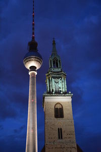 Low angle view of fernsehturm and st mary church against sky at dusk