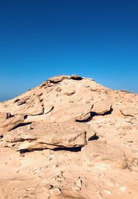 Low angle view of desert against clear blue sky