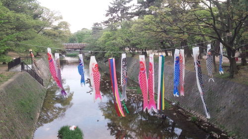 Multi colored decorations hanging on trees against sky