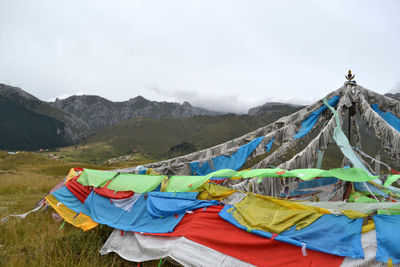 Multi colored flags hanging on mountain against sky