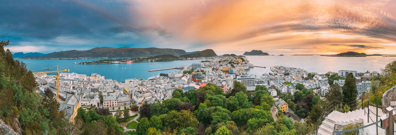 Panoramic view of townscape by sea against sky during sunset