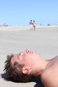 Close-up of young man lying on sand at beach