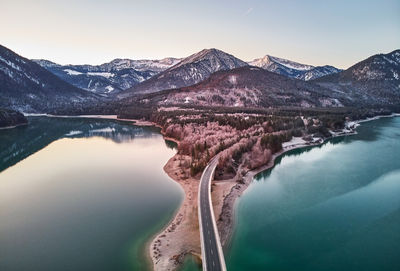 Bridge over lake and mountains against sky