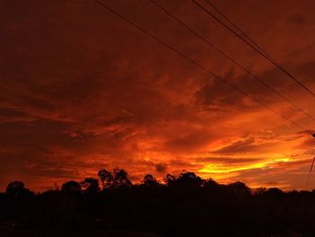 Low angle view of silhouette trees against dramatic sky