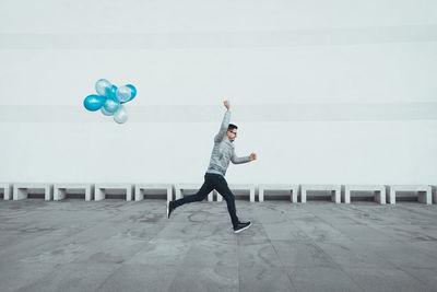 Full length of young man running with balloons