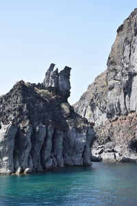 Rock formations in sea against clear sky