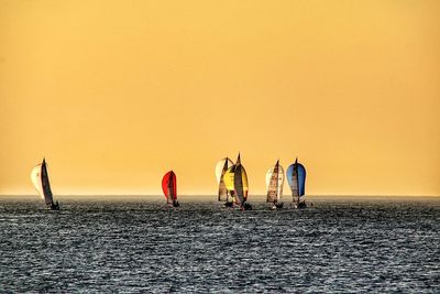 Ship sailing in sea against clear sky during sunset