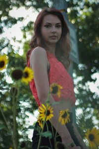 Portrait of beautiful woman standing by flower tree