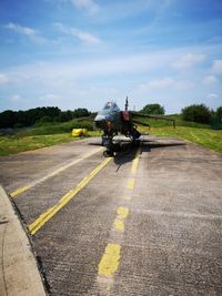 Motorcycle on airport runway against sky