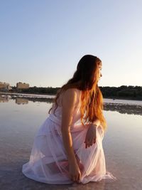 Woman at beach against clear sky during sunset