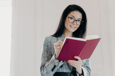 Portrait of young woman holding eyeglasses