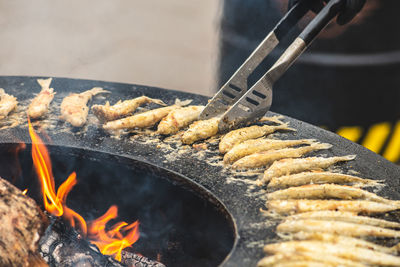 Preparing traditional tasty fried european smelt fish cooked on an open fire in a street food market