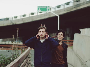 Mischievous friend gesturing horn sign on friend head