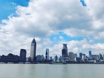 City at waterfront against cloudy sky