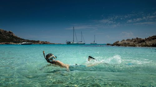 Boy swimming in sea against sky