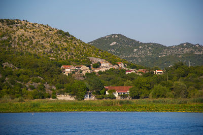 Houses by trees and mountains against sky