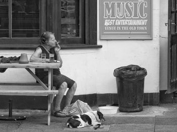 Woman with dog sitting in front of building