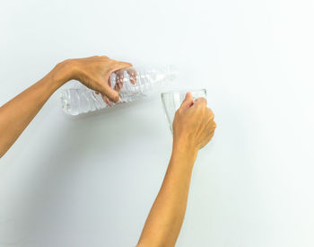 Close-up of hand holding glass over white background