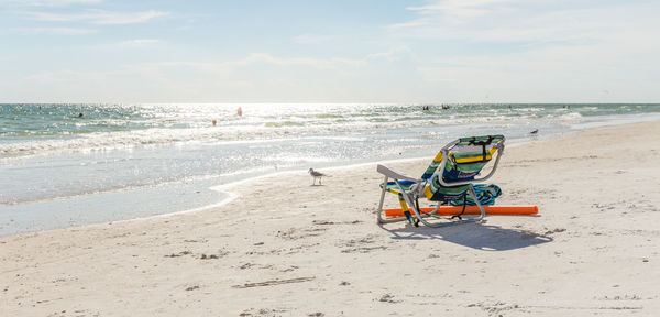 Deck chairs on beach against sky