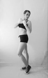 Full length of young woman standing against white background