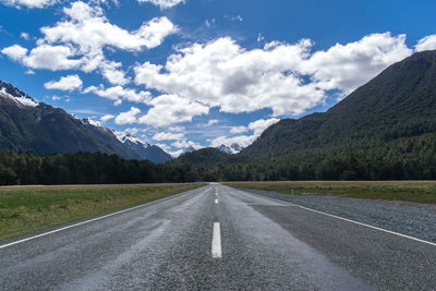 Road by mountains against sky