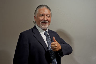 Portrait of a smiling young man standing against wall