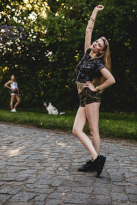 Portrait of beautiful woman standing on footpath with friend in background