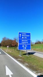 Information sign by road against blue sky