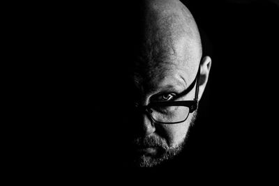 Close-up portrait of serious man against black background