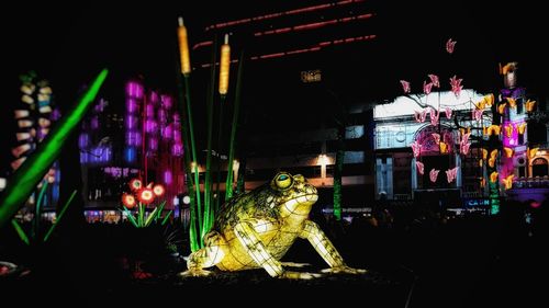 Statue of illuminated ferris wheel at night