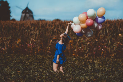 Low section of woman with balloons standing on field