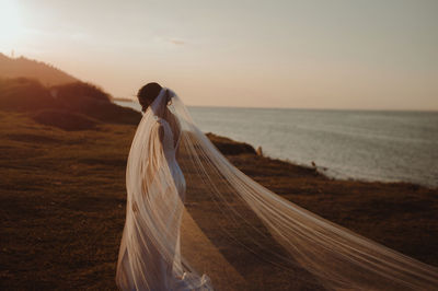 Woman on beach against sky during sunset