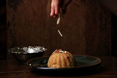 Midsection of person holding ice cream in plate on table