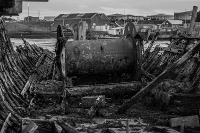 Old ruins of boat at beach against houses